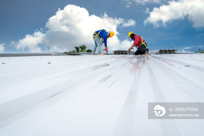 Teamwork of Construction worker install new roof, Electric drill used on new roofs with white Metal Sheet. Roofing tools, Safety body construction, Working at height equipment. building