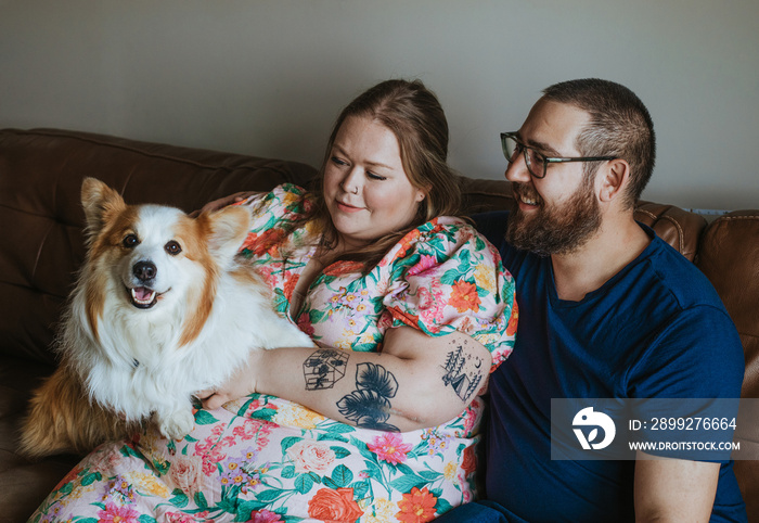 couple sits on couch and holds dog