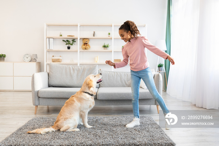 Black girl training and giving treat to her obedient dog