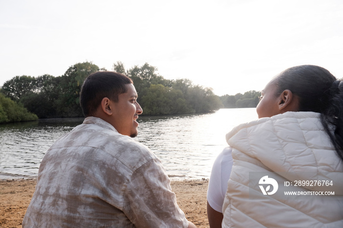 Rear view of couple sitting on lakeshore