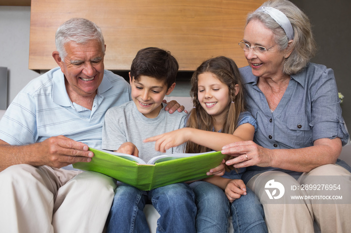 Happy grandparents and grandkids looking at album photo