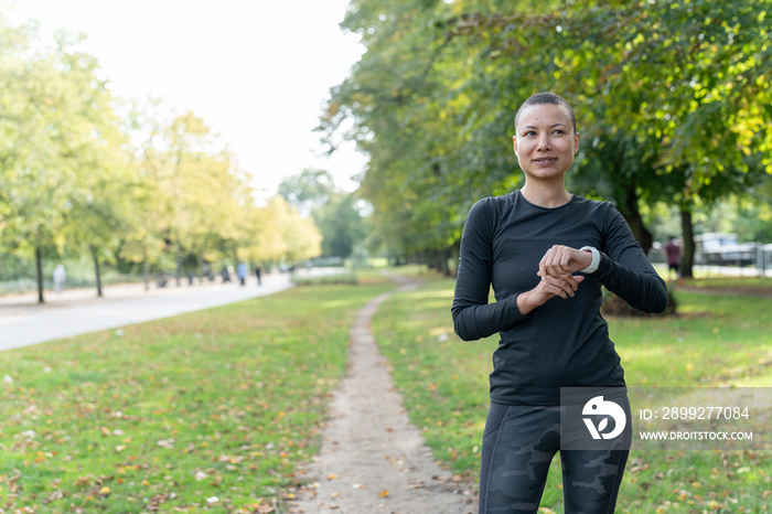 Portrait of athletic woman checking smart watch in park