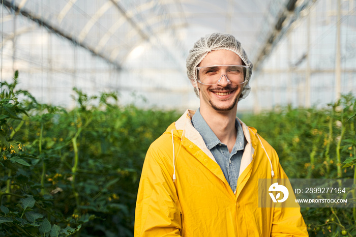 Happy young agronomist enjoying working in hothouse