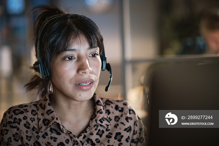 Friendly female call-center agent with headset working on support hotline in the office