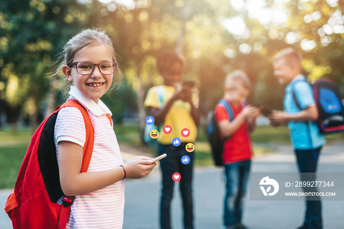 Group of happy elementary school students with smartphones. Primary education, friendship, childhood, and technology concept.