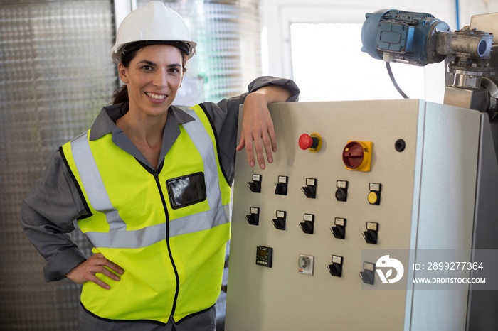 Portrait of female technician standing near machine