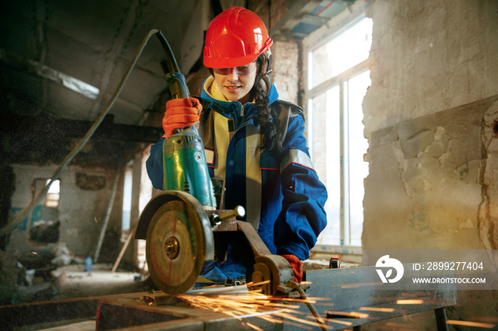 Destroying gender stereotypes. Woman wearing helmet using different male work tools. Gender equality. Girl working at flat remodeling. Building, repair and renovation. woman in the male profession