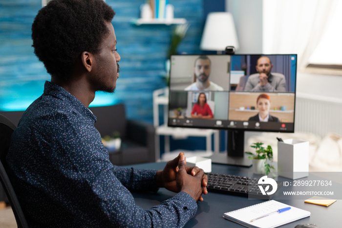 Man of african ethnicity using conference webcam communication to connect via internet with coworkers while working from home. Black person remote worker chatting about job duties