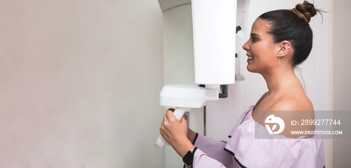 Portrait of female patient doing X-ray orthopantomography with panoramic teeth in dental clinic. Copy space for text