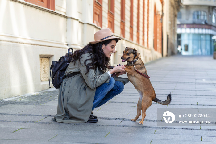 happy hipster woman playing with her dog on the street. stylish girl with funny dog resting, hugging and having fun, cute moments. space for text