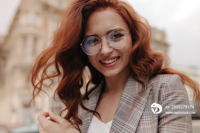 Pretty woman in eyeglasses and jacket looking into camera