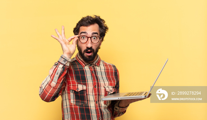 young crazy bearded man surprised expression and a laptop