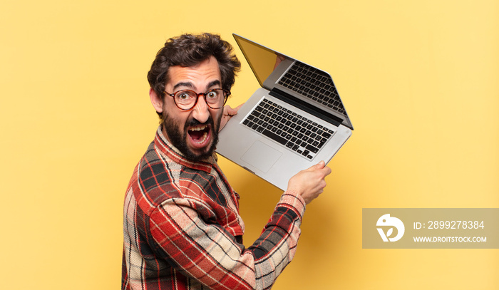 young crazy bearded man angry expression and a laptop