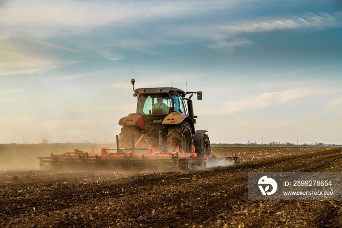 Tractor cultivating field at spring