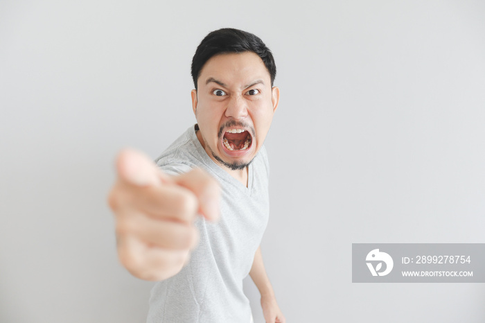 Angry face of man in grey t-shirt with hand point on empty space.