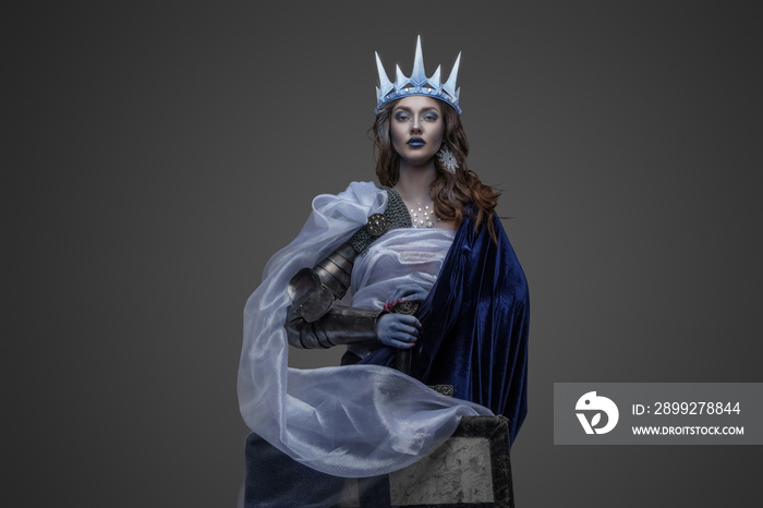 Shot of frozen queen with sword and shield dressed in cloak and make up.