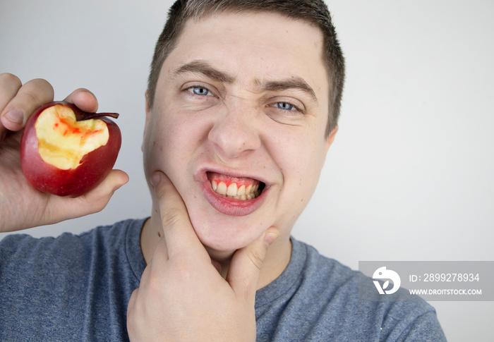 A man bit an apple and blood came out of his gums. Gum bleeding, symptoms of gingivitis, periodontitis and periodontal disease.