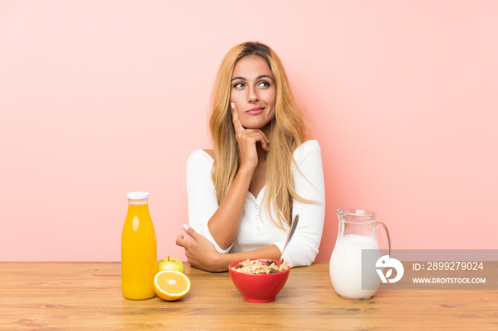 Young blonde woman having breakfast milk thinking an idea