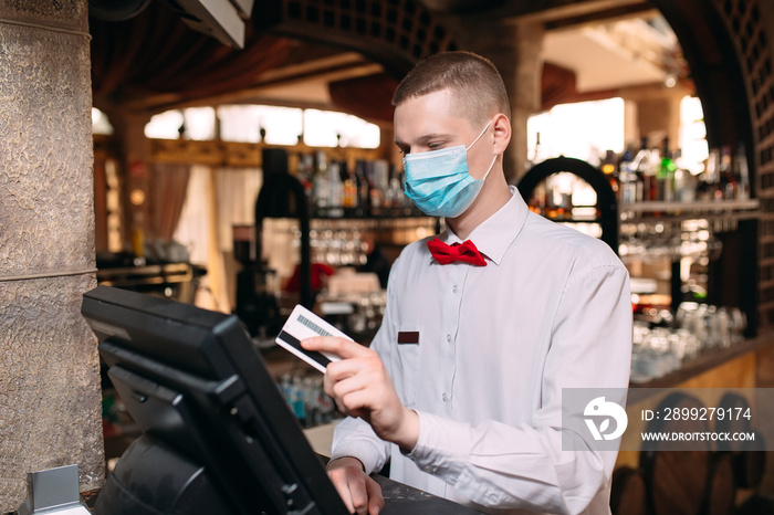 small business, people and service concept. man or waiter in medical mask at counter with cashbox working at bar or coffee shop.