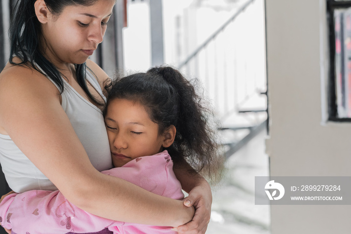 beautiful little brown-skinned latina girl hugging her mother tenderly and proud to have her by her side. daughter thanks her mother for all the love she gives her. concept of home