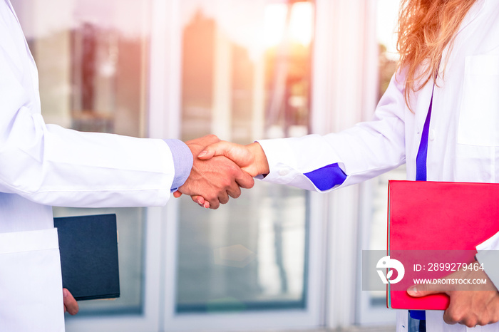 Doctors handshake at hospital room entrance -  Hand gesture between medical staff close up image