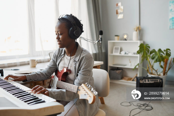 Minimal portrait of young black woman playing synthesizer and composing music at home, copy space