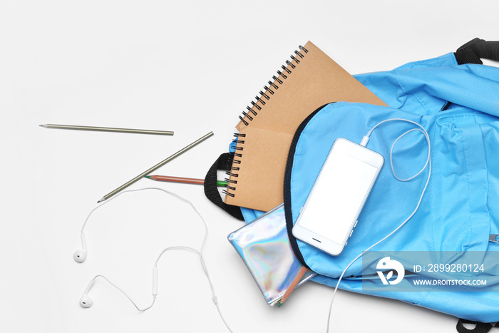 Set of school supplies with backpack and mobile phone on white background