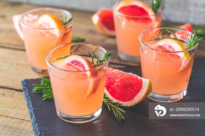 Fresh pink alcoholic cocktail with grapefruit, ice and rosemary