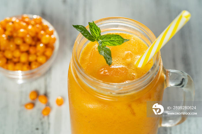 Fresh organic yellow smoothie in glass mug on white wooden table, close up. Refreshing summer fruit drink. The concept of healthy eating. Sea buckthorn smoothie