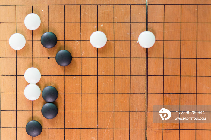 Game’s white and black stone on cross board.