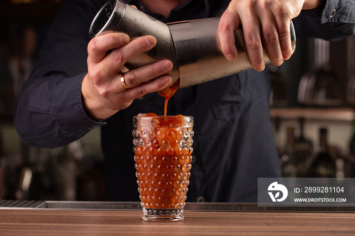 bartender pours tomato red juice from the shaker, making a cocktail, drink