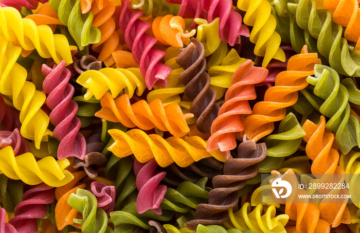 Background of colorful pasta texture close-up. Assortment of colorful macaroni. italian pasta. Variety of types and shapes of dry Italian pasta. Full background of dry uncooked macaroni.