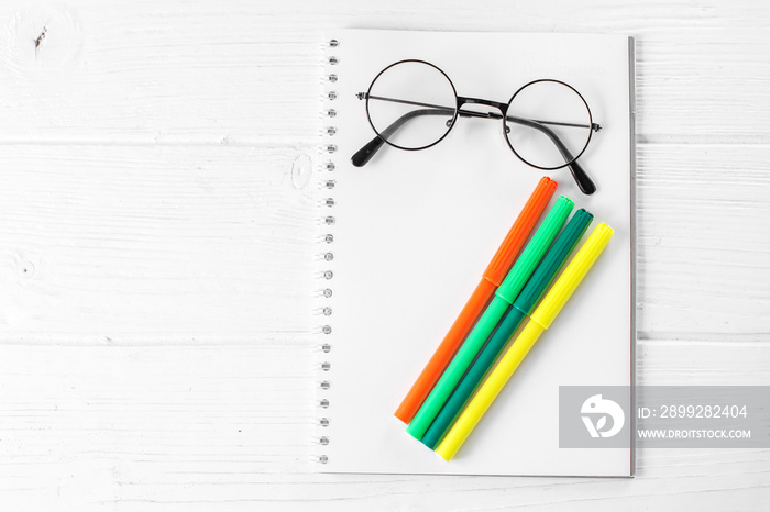 Green and yellow markers, notebook and glasses. The concept of school, creativity, childhood.