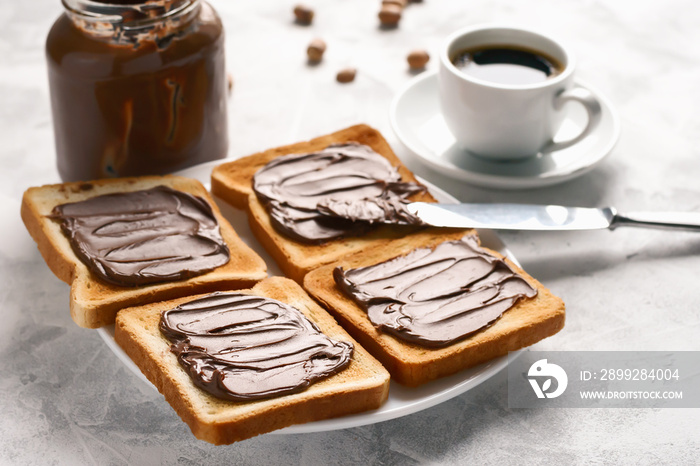 Bread toast spread with chocolate-nut paste spread in a plate on the table