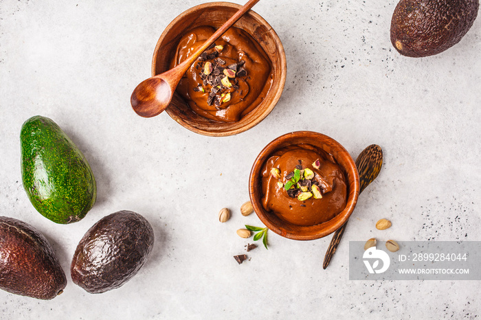 Avocado chocolate mousse with pistachios in wooden bowl on white background.