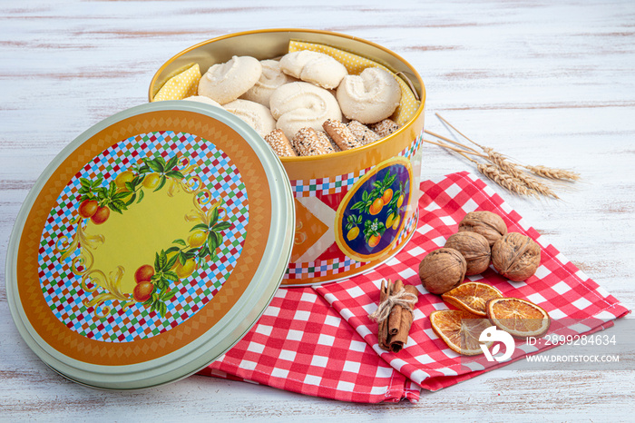 Cookies in metal box. Biscuits in a tin box with colored cover. Open Round box with cookies on wooden background.