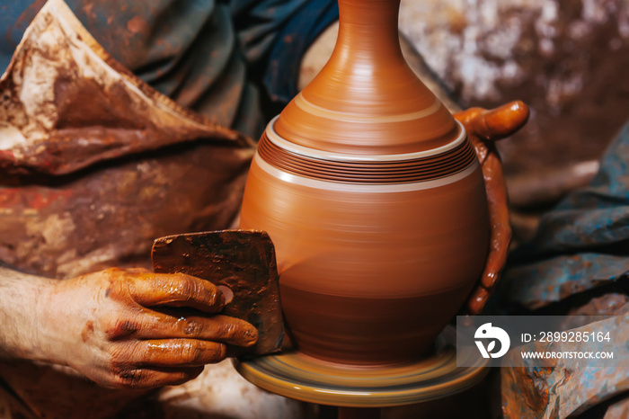 Hands of making clay pot on the pottery wheel ,select focus, close-up.