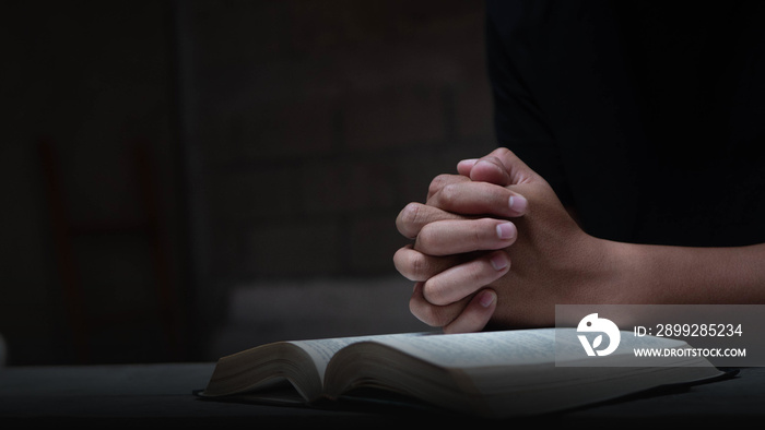 Hands folded in prayer on a Holy Bible in church concept for faith, spirituality and religion, Man hands praying on holy bible in the morning, Christian life crisis prayer to God.