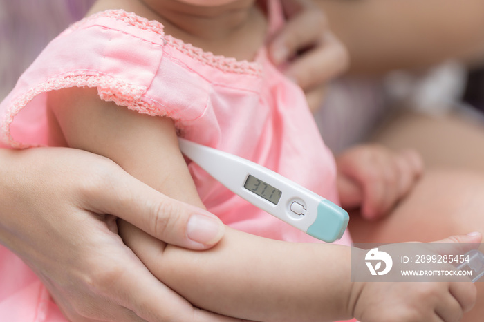 Mother check fever her infant at home, measuring temperature to a baby