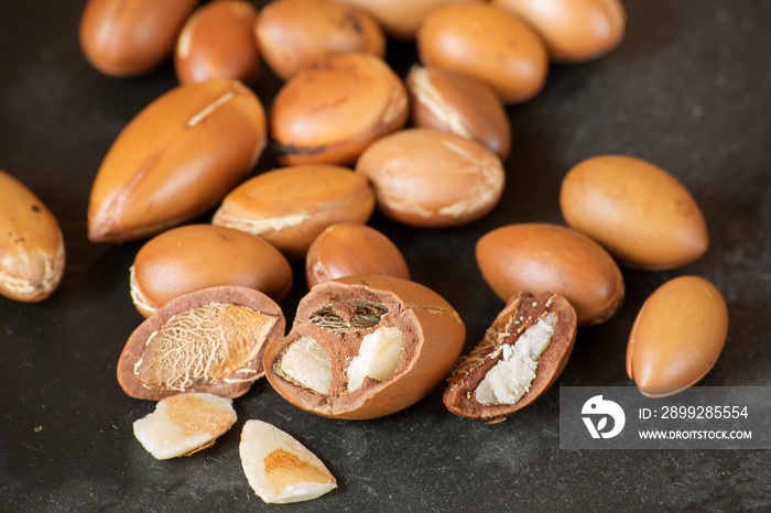 the kernel of the argan nut is broken on a black background with whole nuts, close-up