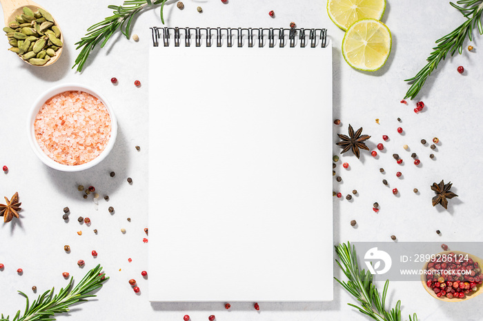 Assortment of spices and herbs and blank notepad on white kitchen table. Recipe book template. Culinary blog social media concept.