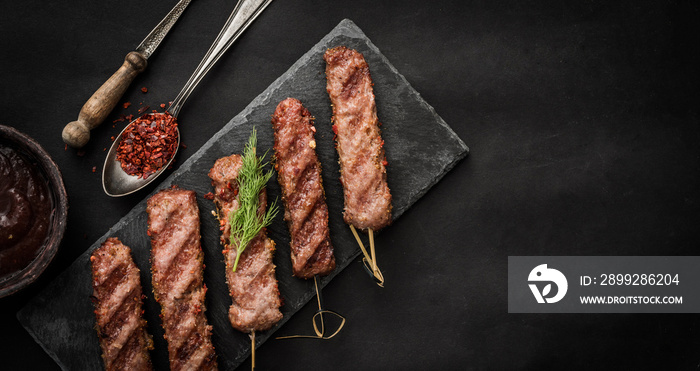 Grilled kebab with spices and sauce on a dark background