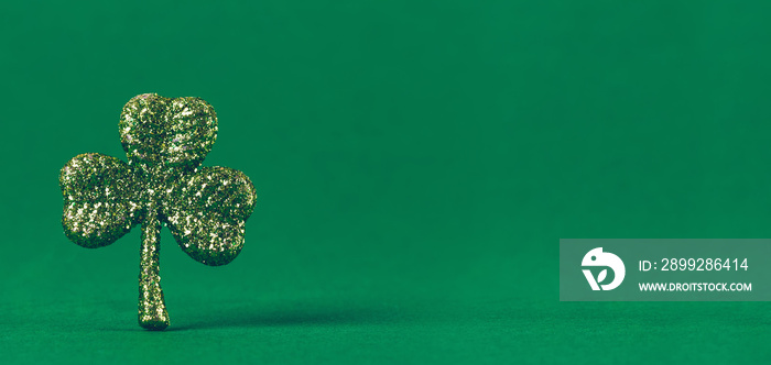 Glitter shamrock on green paper background. St Patricks day symbol. Irish National holiday concept