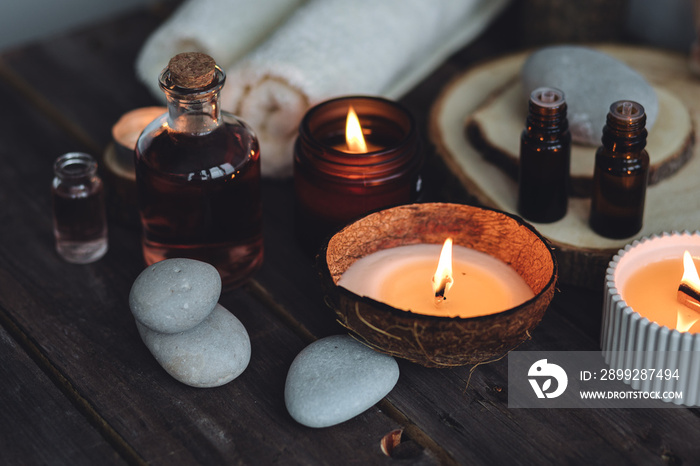 Concept of natural essential organic oils, Bali spa, beauty treatment, relax time. Atmosphere of relaxation, pleasure. Candles, towels, dark wooden background. Alternative oriental medicine