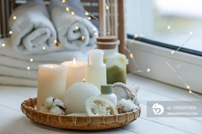 Beautiful burning candles with cosmetic products on windowsill