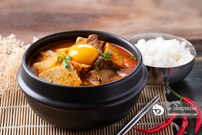 Korean food, Kimchi soup with tofu, pork and fresh egg yolk in Korean stone pot