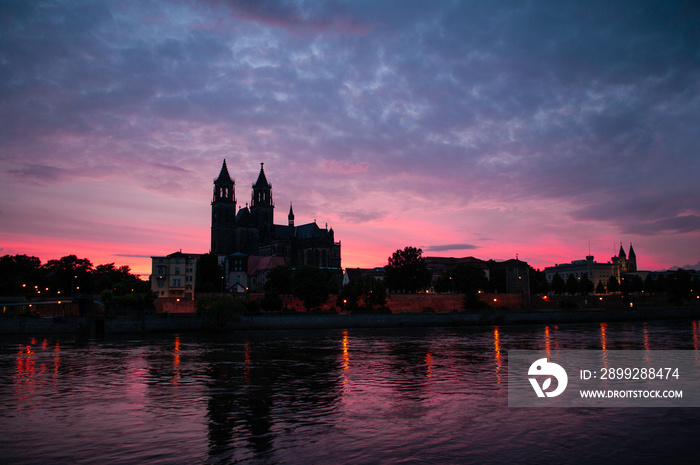 Silhouette of a medieval castle at beautiful bloody sunset at historical downtown of Magdeburg, old town, Elbe river and Magnificent Cathedral, Germany.