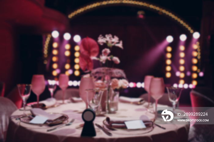 Romantic dinner pink decor table at restaurant with stage. Blurred, bokeh, background