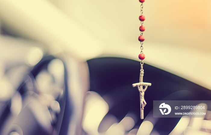 Cross in the car. The concept of religiosity and faith in safe driving. A rosary with a cross hangs on the mirror, faith in God and providence.