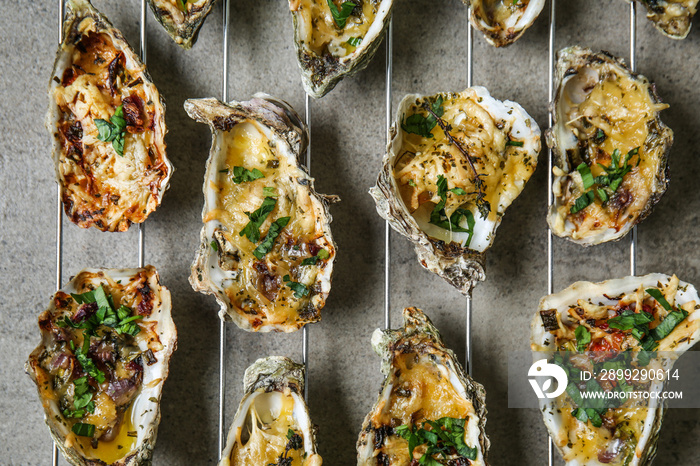 Cooling rack with tasty baked oysters on grey background